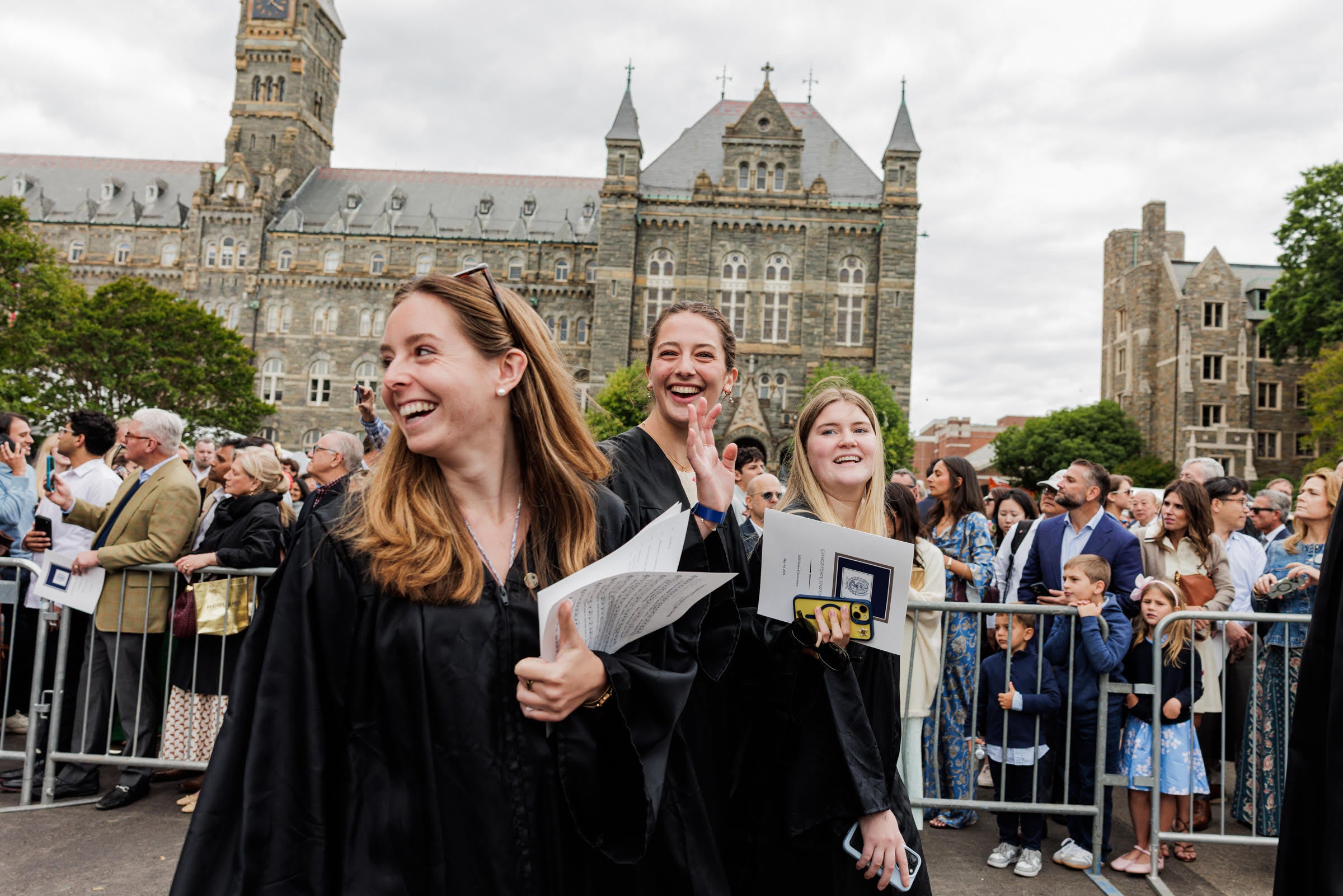 Three graduates smiling in front of Healy Hall at the Class of 2026 Convocation.